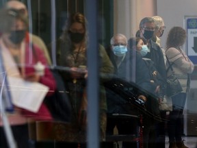 People wear masks while in line at the RBC Convention Centre, in Winnipeg.  There is a vaccine clinic at that location. Tuesday, March 23, 2021.