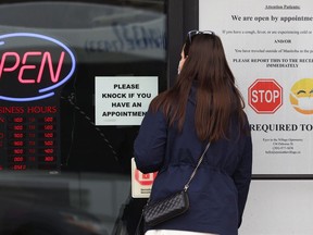 A woman waits outside the office of an optometrist in the Osborne Village area of Winnipeg on Tuesday, March 23, 2021.