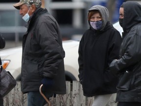 A group of people wear masks as they walk along a street, in Winnipeg on Friday, March 26, 2021.