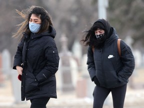 People crossing a street in strong winds, in Winnipeg on Tuesday.