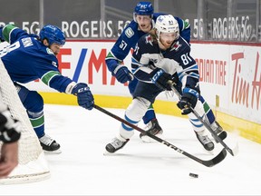 Kyle Connor (81) of the Winnipeg Jets controls the puck against Jordie Benn (8) and Tyler Myers (57) of the Vancouver Canucks during the first period of NHL action at Rogers Arena on March 22, 2021 in Vancouver.