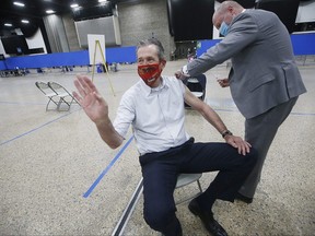 Manitoba Premier Brian Pallister waves to vaccination staff in Winnipeg’s convention centre as Dr. Brent Roussin, chief provincial public health officer, prepares to give him his COVID-19 vaccination Thursday, April 8, 2021. John Woods/Pool/The Canadian Press