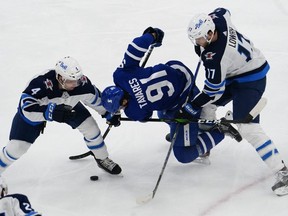 Maple Leafs captain John Tavares gets double-teamed by Neal Pionk (left) and Adam Lowry of the Jets during last night’s game at Scotiabank Arena.  John E. Sokolowski/USA TODAY Sports