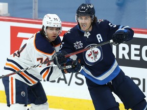 Jets centre Mark Scheifele (right) is guarded by Edmonton Oilers defenceman Ethan Bear in Winnipeg on Monday.