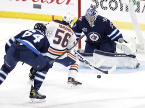 Winnipeg Jets defenceman Logan Stanley (64) chases down Edmonton Oilers winger Kailer Yamamoto as he shoots on goaltender Connor Hellebuyck during the first period on Saturday at Bell MTS Place.