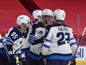 Winnipeg Jets forward Andrew Copp (9)  celebrates with forward Mathieu Perreault (85) and forward Nikolaj Ehlers (27) after scoring a goal against the Montreal Canadiens during the third period at the Bell Centre in Montreal on Saturday, April 10, 2021.