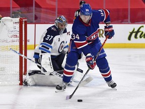 Montreal Canadiens forward Corey Perry (94) plays the puck against Winnipeg Jets goalie Connor Hellebuyck (37) during the second period at the Bell Centre in Montreal on Saturday, April 10, 2021.
