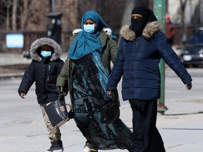 People wear masks while crossing a street, in Winnipeg on Thursday, April 1, 2021.
