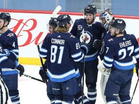 Winnipeg Jets centre Pierre-Luc Dubois (centre) and teammates congratulate goaltender Connor Hellebuyck after the Jets hung on to beat the Ottawa Senators in Winnipeg on Monday.