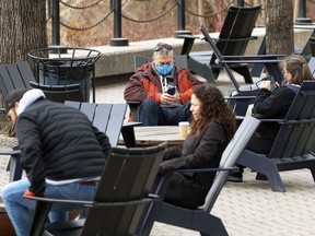 People lounge in the patio space at The Forks in Winnipeg on Sunday, April 11, 2021.