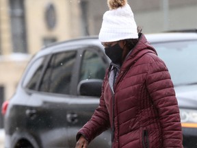 A person wears a mask while walking through Winnipeg following a spring snowstorm on Tuesday, April 13, 2021.
