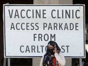 A person stands in front of a large sign for a vaccine clinic in Winnipeg on Tuesday. Chris Procaylo/Winnipeg Sun