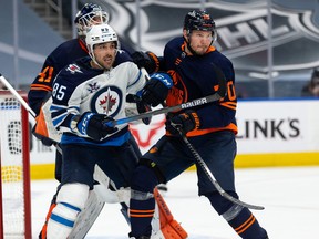 Edmonton Oilers’ Dmitry Kulikov (70) battles Winnipeg Jets’ Mathieu Perreault (85) during the second period of NHL North Division playoff action at Rogers Place in Edmonton, on Wednesday, May 19, 2021.