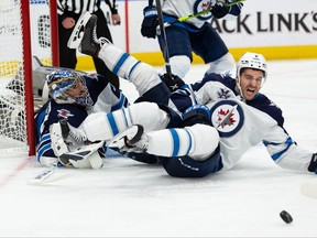 Winnipeg Jets’ defenceman Dylan DeMelo (2) comes to the aid of his goaltender Connor Hellebuyck (37) to makes a save against the Edmonton Oilers during the third period of Game 2 of their NHL North Division playoff series at Rogers Place in Edmonton, on Friday, May 21, 2021.