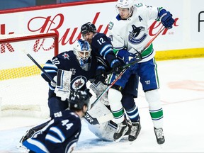 Jets forward Jansen Harkins (12) jostles for position with Canucks defenceman Tyler Myers (57) during the second period at Bell MTS Place on Monday.