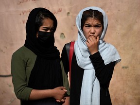 School girls stand near the site of yesterday's multiple blasts outside a girls' school in Dasht-e-Barchi on the outskirts of Kabul on May 9, 2021.