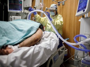 Respiratory therapist Flor Guevara adjusts a breathing tube for a patient suffering from COVID-19 at Humber River Hospital's Intensive Care Unit, in Toronto on April 29, 2021.