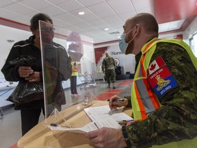Capt. Kevin Little registers a community member for vaccination at the Nisichawayasihk Cree Nation clinic. Members of the Land Task Force support a COVID-19 vaccination clinic for the second dose in Nisichawayasihk Cree Nation in northern Manitoba during Operation VECTOR on May 7, 2021.