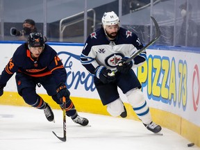 Ethan Bear #74 of the Edmonton Oilers and Nate Thompson #11 of the Winnipeg Jets chase the puck during Game One of the First Round of the 2021 Stanley Cup Playoffs at Rogers Place on May 19, 2021 in Edmonton, Canada.