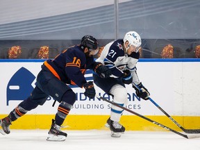 Jujhar Khaira of the Edmonton Oilers battles against Dominic Toninato of the Winnipeg Jets during Game One of the First Round of the 2021 Stanley Cup Playoffs at Rogers Place on May 19, 2021 in Edmonton.