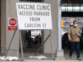 A man wearing a mask walks by the COVID-19 vaccination supersite at RBC Convention Centre in Winnipeg on Sunday, May 2, 2021.