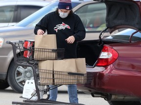A person wears a mask while loading grocery items in Winnipeg on Tuesday.