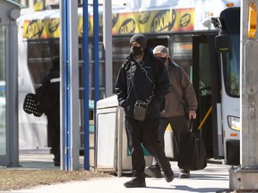 Men wearing masks step off a bus on Osborne Street at Broadway in Winnipeg on Wednesday. KEVIN KING/Winnipeg Sun/Postmedia Network