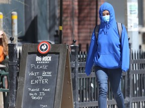 A person wears a mask while walking past a patio, in Winnipeg on Saturday.