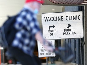 A cyclist rides by a sign at the COVID-19 vaccination site in the RBC Convention Centre in Winnipeg on Tues., May 11, 2021. KEVIN KING/Winnipeg Sun/Postmedia Network