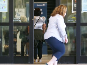A woman walks past the main entrance to the provincial COVID-19 vaccination site at RBC Convention Centre while others wait in line in Winnipeg on Tuesday. KEVIN KING/Winnipeg Sun/Postmedia Network