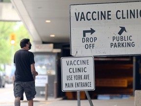 A man walks by a sign outside the COVID-19 vaccination site at RBC Convention Centre in Winnipeg on Sunday, May 23, 2021.