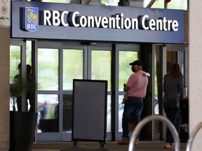 A man carries a child into the RBC Convention Centre, home to a COVID-19 vaccination site, in Winnipeg on Tues., May 25, 2021. KEVIN KING/Winnipeg Sun/Postmedia Network