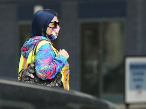 A woman wearing a mask waits to cross the street near the COVID-19 vaccination site at RBC Convention Centre in Winnipeg on Tues., May 25, 2021. KEVIN KING/Winnipeg Sun/Postmedia Network