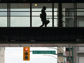 A woman wearing a mask walks across the overpass at RBC Convention Centre in Winnipeg on Tues., May 25, 2021. KEVIN KING/Winnipeg Sun/Postmedia Network