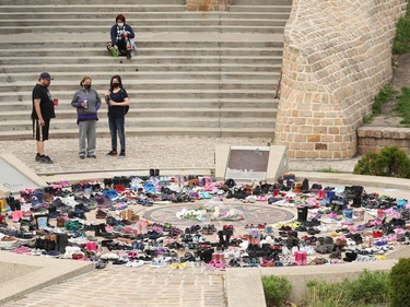 People observe a memorial to the 215 children killed at a residential school in Kamloops, B.C., at the Oodena Circle at the Forks in Winnipeg, on Sunday, May 30, 2021.