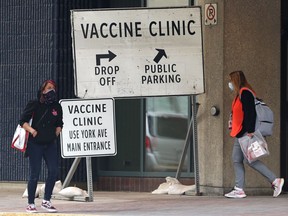 People walking near a sign at the COVID-19 vaccination site at RBC Convention Centre in Winnipeg on Sunday. On Monday afternoon the facility was evacuated due to a potential gas leak and vaccination appointments will have to be rescheduled.