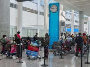 Passengers from New Delhi wait in long lines for transportation to their quarantine hotels at Pearson Airport in Toronto on Friday April 23, 2021.