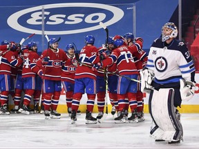 The Montreal Canadiens celebrate an overtime victory as goaltender Connor Hellebuyck #37 of the Winnipeg Jets skates by in Game Four of the Second Round of the 2021 Stanley Cup Playoffs at the Bell Centre on June 7, 2021 in Montreal, Canada.  The Montreal Canadiens defeated the Winnipeg Jets 3-2 in overtime and eliminated them with a 4-0 series win.  (Photo by Minas Panagiotakis/Getty Images)