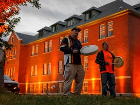 Thundersky Justin Young, left, and Daryl Laboucan drum and sing healing songs at a makeshift memorial to honour the 215 children whose remains have been discovered buried near the former Kamloops Indian Residential School in Kamloops, B.C., on June 2, 2021.