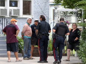Police speak to people in a front yard not far from where a 12-year-old boy was stabbed to death the night before, on   Saturday, June 19, 2021.