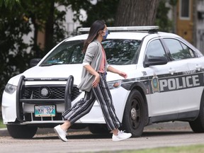 A person walks past a police car Saturday not far from where a 12-year-old boy was stabbed to death the night before.