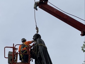 A worker removes a statue of Sir John A. Macdonald