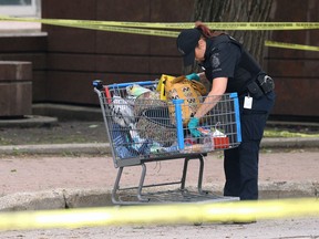 A forensic identification unit officer sifts through a shopping cart at a homicide scene on Kennedy Street near Ellice Avenue on Thursday. Police were alerted to a man who had been shot just after midnight. The victim has been identified as Marlon Jose Chamorro-Gonzales.