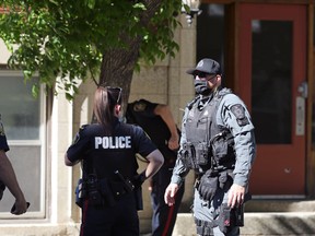 A member of the Winnipeg Police Service tactical support team speaks with officers at a shooting scene near the intersection of Young Street and Balmoral Avenue in Winnipeg on Monday, June 14, 2021. Police would only say that a victim of a gunshot wound was transported to hospital.