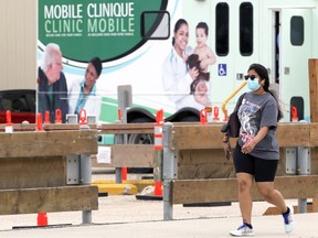 A woman wearing a mask walks past a mobile COVID-19 testing site on Portage Avenue in Winnipeg on Sunday, June 20, 2021.