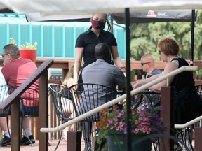 A waitress attends to a table on a patio at The Forks in Winnipeg on Sunday, June 27, 2021.
