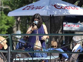 A woman wears a mask as she takes a table on the patio at Bar Italia on Corydon Avenue in Winnipeg on Monday, June 28, 2021.