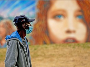 A masked man takes a stroll at Giovanni Caboto Park in Edmonton on Friday July 16, 2021.