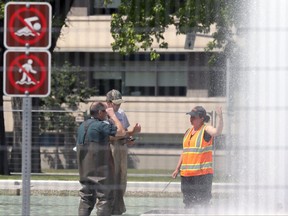 A crew in hip waders test out the fountains at Memorial Park in Winnipeg on Thursday, June 24. The province announced Friday the completion of extensive repairs and refurbishing of the Memorial Park fountain.