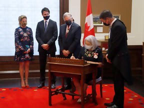 Mary Simon signs an oath as her husband Whit Fraser, Prime Minister Justin Trudeau and wife Sophie Gregoire, and speaker of the house Anthony Rota look on after she was sworn in as the first indigenous Governor General during a ceremony in Ottawa on July 26, 2021.